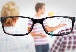 Looking through glasses at a room with people presenting