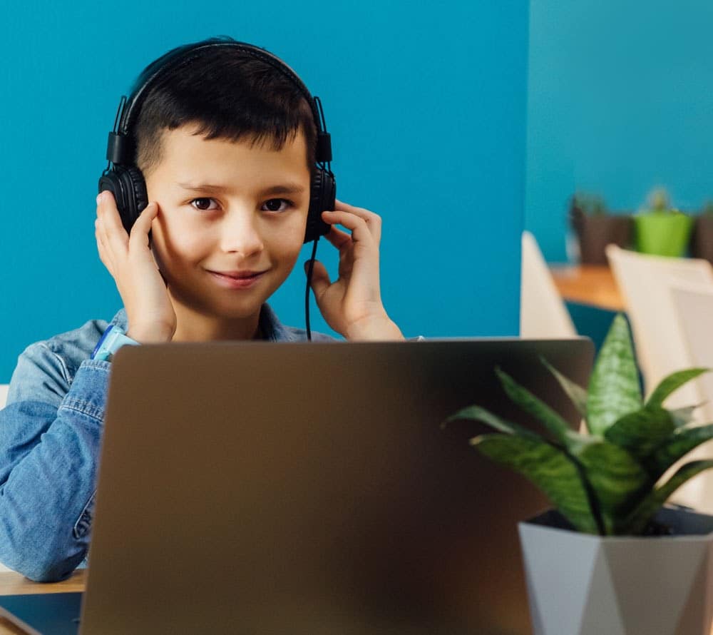 Young boy on a laptop smiling with headphones on